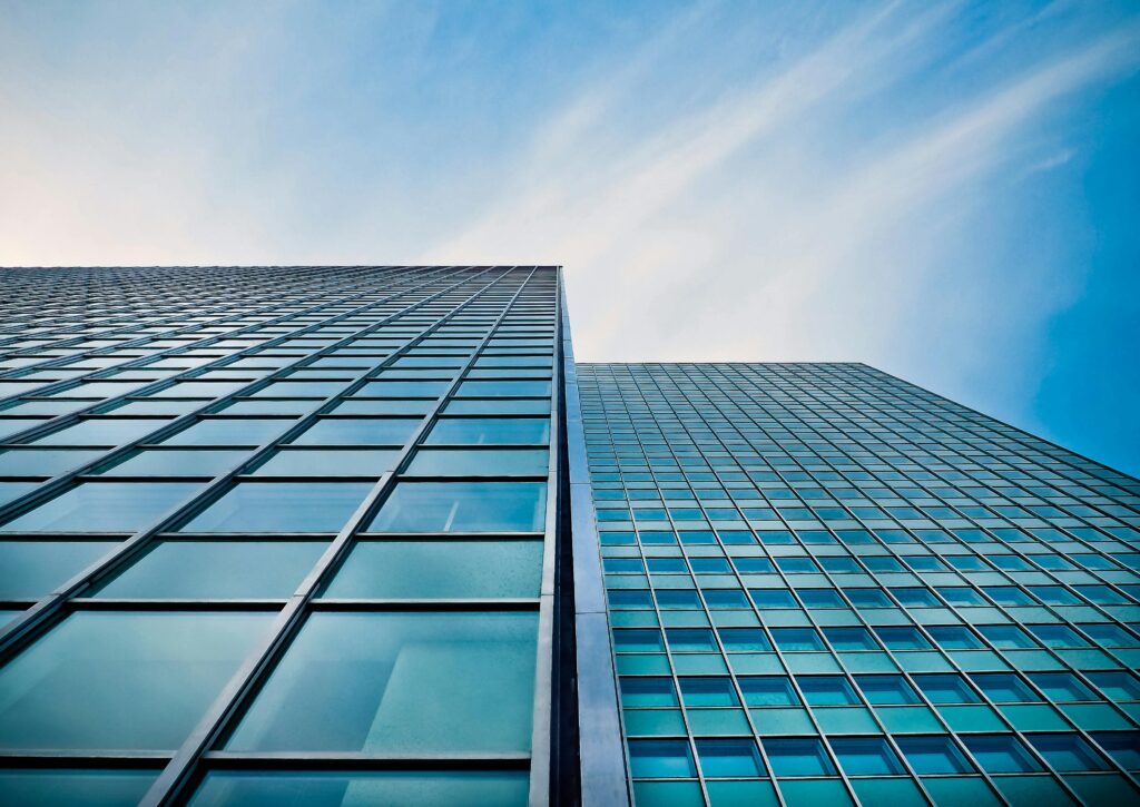 A low angle view of a modern glass skyscraper against a clear blue sky.