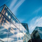 Low angle view of contemporary glass office buildings reflecting a vibrant blue sky.