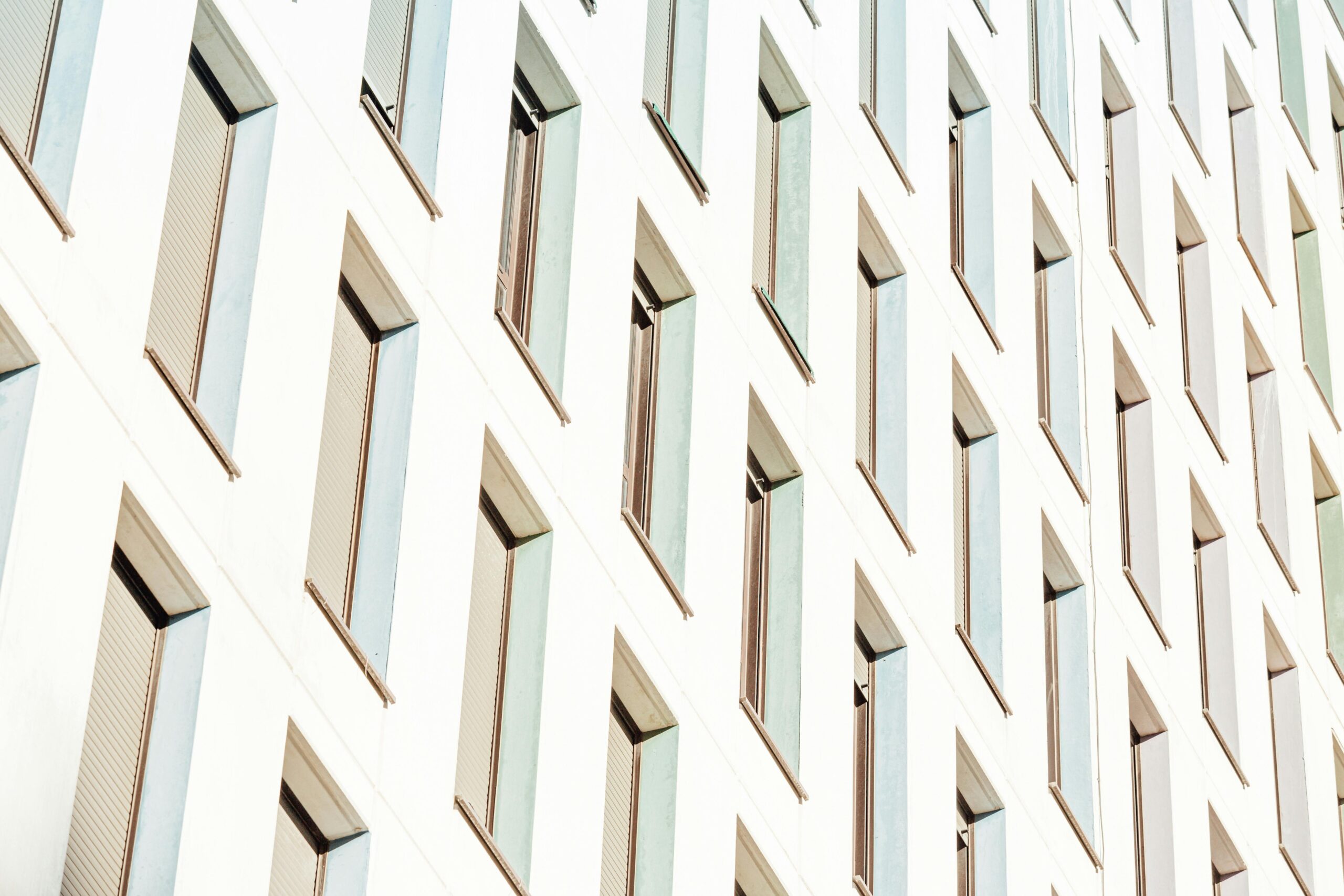 From below of lots of long narrow identical windows of contemporary construction in sunlight