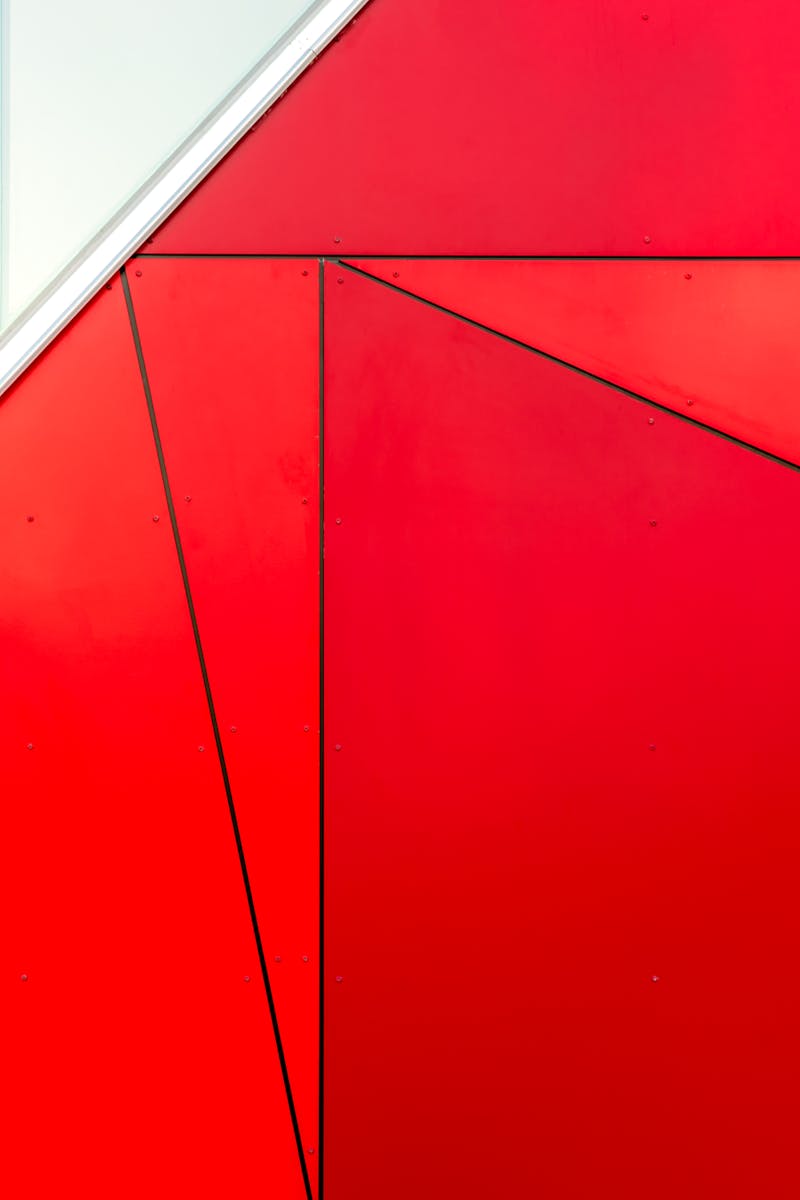 Abstract red geometric facade with triangular patterns and cladding in a contemporary design.