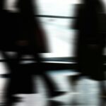 Abstract blurred motion of people walking indoors, depicting urban life and busy routines.