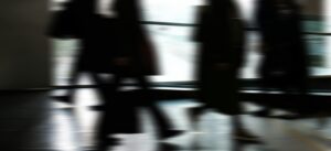 Abstract blurred motion of people walking indoors, depicting urban life and busy routines.