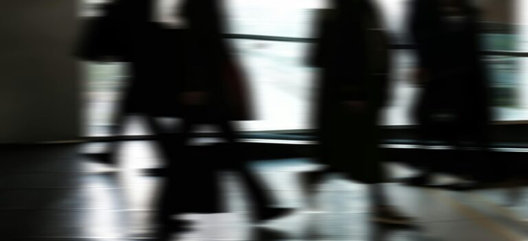 Abstract blurred motion of people walking indoors, depicting urban life and busy routines.