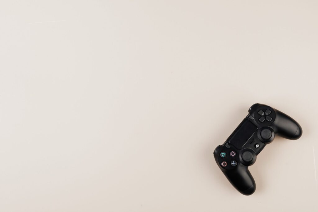 Black PlayStation controller on a neutral background with ample copy space.