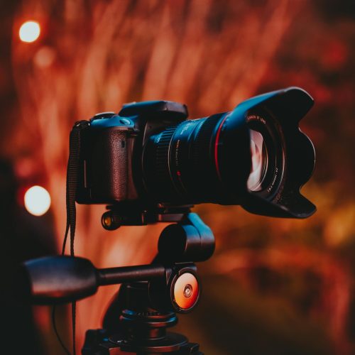 Close-up of a professional camera mounted on a tripod with warm lighting, perfect for capturing outdoor scenes.