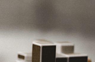 A close-up of a hand holding a complex wooden puzzle toy, symbolizing mental challenges.