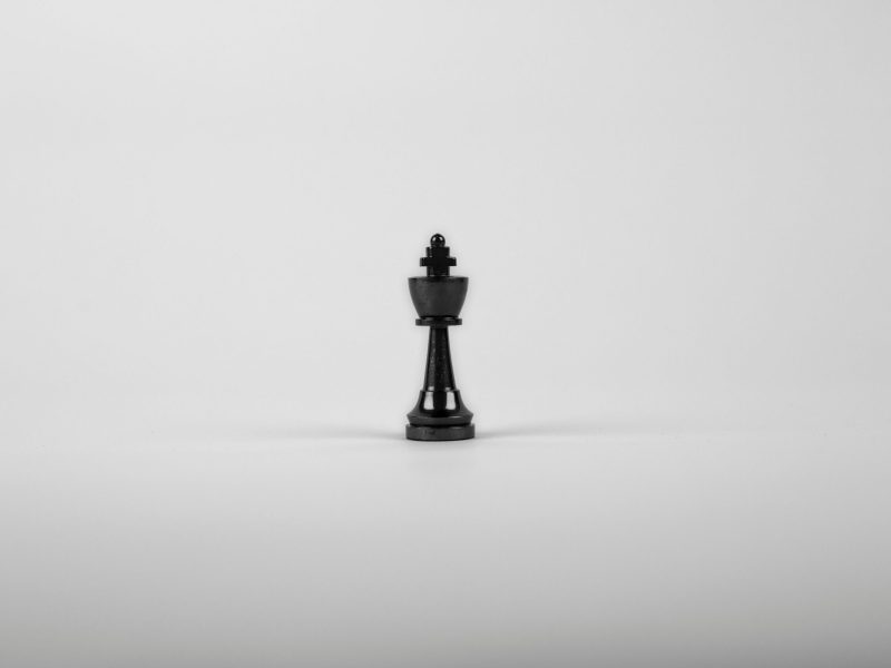 A minimalist black chess king piece on a white background, representing strategy and power.