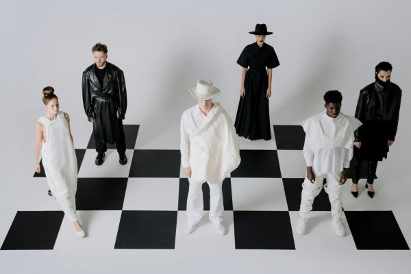 Stylish fashion models in black and white outfits on a chessboard backdrop.