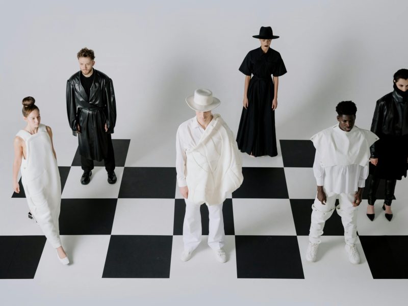 Stylish fashion models in black and white outfits on a chessboard backdrop.